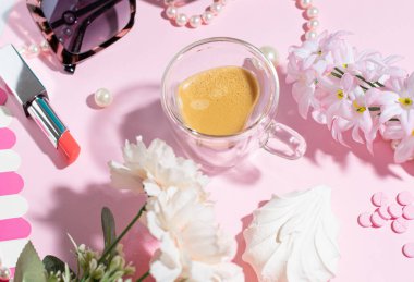 Çiçekli kahve masası, inciler, kozmetik ürünler ve bir fincan kahve.