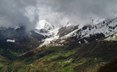 View of the snow-capped Pyrenees and village in south-west France clipart