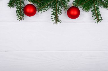 Noel ağacı dalları, beyaz ahşap masa üzerindeki balolar ve süslemeler, üst manzara, metin için boşluk.