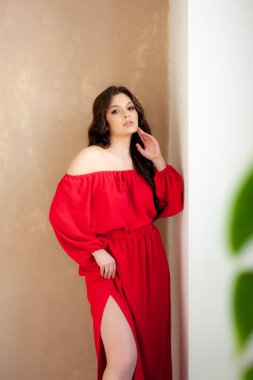 Uzun kırmızı elbiseli, güzel, gülen kadın şehvetli poz veriyor.