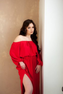 Uzun kırmızı elbiseli, güzel, gülen kadın şehvetli poz veriyor.