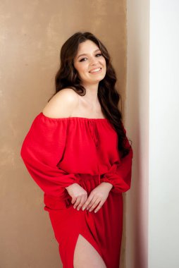 Uzun kırmızı elbiseli, güzel, gülen kadın şehvetli poz veriyor.