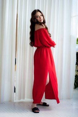 Uzun kırmızı elbiseli, güzel, gülen kadın şehvetli poz veriyor.