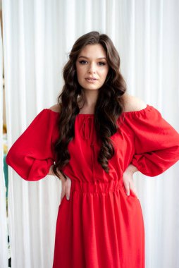 Uzun kırmızı elbiseli, güzel, gülen kadın şehvetli poz veriyor.