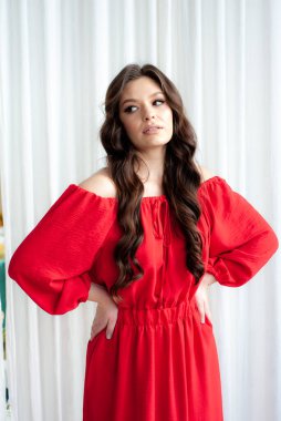 Uzun kırmızı elbiseli, güzel, gülen kadın şehvetli poz veriyor.