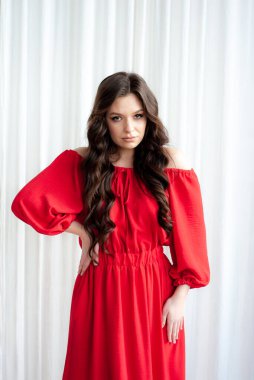 Uzun kırmızı elbiseli, güzel, gülen kadın şehvetli poz veriyor.