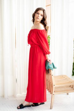Uzun kırmızı elbiseli, güzel, gülen kadın şehvetli poz veriyor.