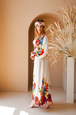 Çiçek buketi olan bir elbise içinde güzel genç bir kadın.