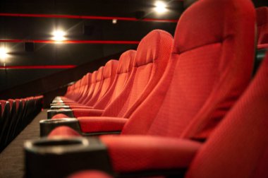 Kırmızı koltukları ve sandalyeleri olan sinema salonu.