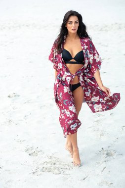 Kumsalda bikinili güzel bir kadın poz veriyor.