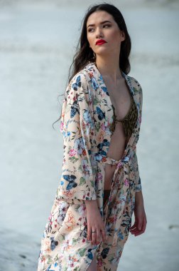 Sahilde elbise giymiş güzel genç bir kadın.