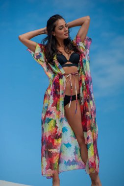 Plajda poz veren mayolu güzel genç bir kadın.