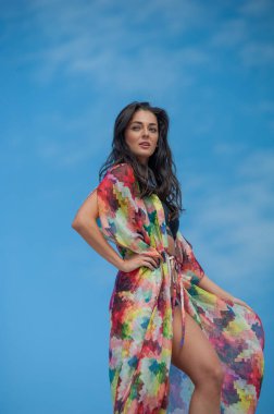 Sahilde elbise giymiş güzel genç bir kadın.