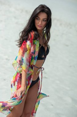 Kumsalda bikinili güzel bir kadın poz veriyor.