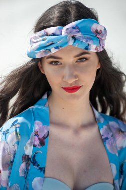 Mavi elbiseli, beyaz gömlekli, kumsalda yaşayan güzel bir kadın.