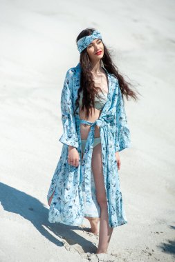 Beyaz elbiseli güzel bir kız ve kumsalda bir şapka.