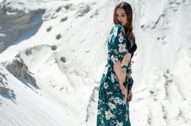 Dağların arka planında beyaz elbiseli güzel genç bir kadın.