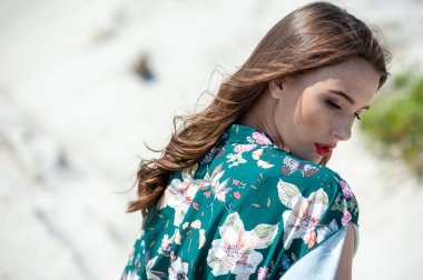 Sahilde atkısı olan beyaz elbiseli güzel bir kadın.