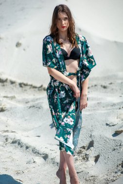 Plajda poz veren mayolu güzel genç bir kadın.