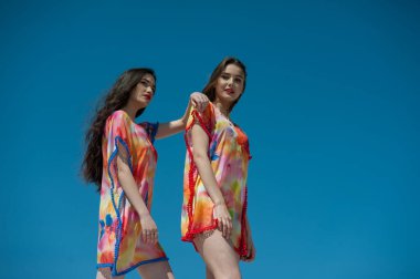 Sahilde su sıçratan mavi elbiseli güzel genç kadınlar.