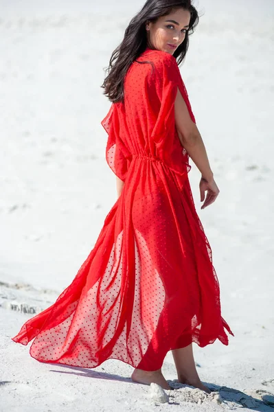 ビーチでポーズをとる赤いドレスの美しい女の子 — ストック写真