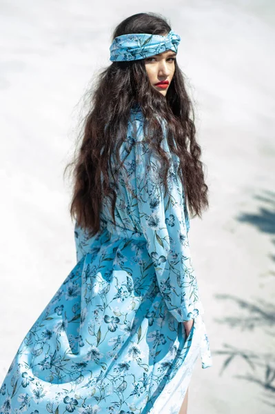 stock image beautiful young woman in a white dress and a blue scarf on the beach