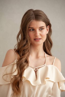 Stüdyoda poz veren uzun kıvırcık saçlı güzel bir genç kadın.