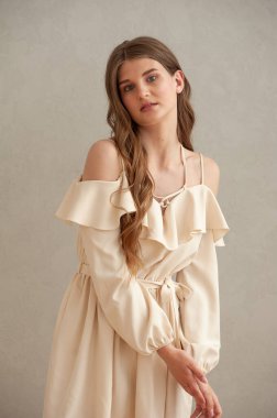 Gri arka planda beyaz elbiseli güzel bir kadın.