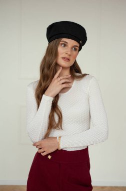 Gri arka planda şık şapkalı güzel esmer kadın. 