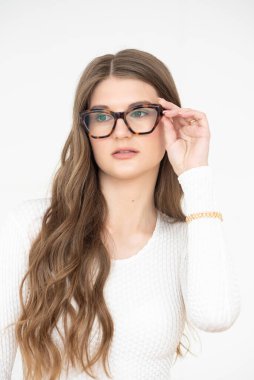 Görme yeteneğini geliştirmek için gözlük takan güzel bir genç kadın portresi. Güzel dalgalı saçlar, gündüz makyajı, parlak bir iç mekanda normal kıyafetler.
