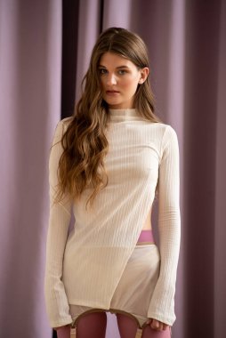 Beyaz bir süveterin arkasında poz veren manken.