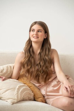 Beyaz arka planda rahat iç çamaşırlarıyla gülümseyen ve başka tarafa bakan kendine güvenen güzel bir genç kadın..