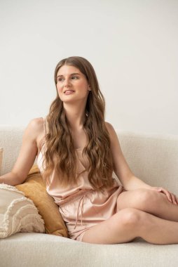 Beyaz arka planda rahat iç çamaşırlarıyla gülümseyen ve başka tarafa bakan kendine güvenen güzel bir genç kadın..