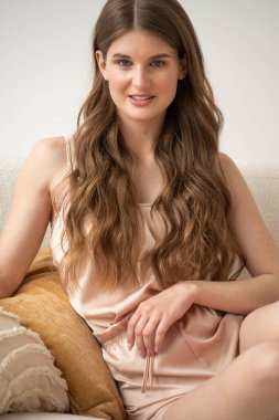 Beyaz arka planda rahat iç çamaşırlarıyla gülümseyen ve başka tarafa bakan kendine güvenen güzel bir genç kadın..