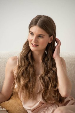 Beyaz arka planda rahat iç çamaşırlarıyla gülümseyen ve başka tarafa bakan kendine güvenen güzel bir genç kadın..