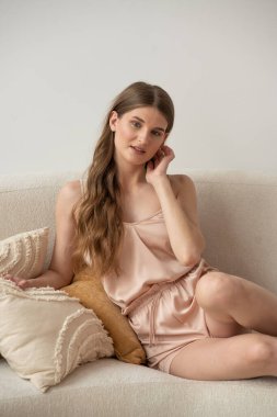 Beyaz arka planda rahat iç çamaşırlarıyla gülümseyen ve başka tarafa bakan kendine güvenen güzel bir genç kadın..