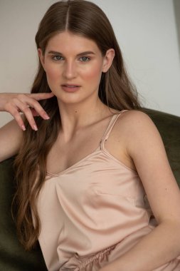 Beyaz arka planda rahat iç çamaşırlarıyla gülümseyen ve başka tarafa bakan kendine güvenen güzel bir genç kadın..