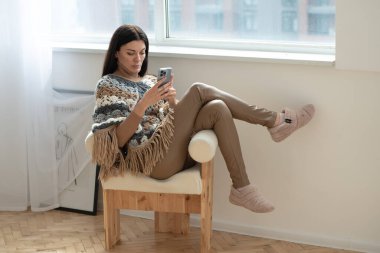 Kanepede oturan ve cep telefonu kullanan güzel genç bir kadın.