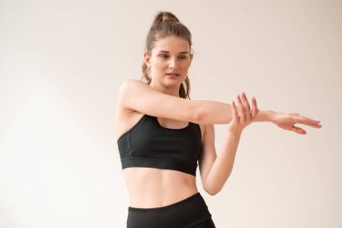 Genç ve güzel bir kadın beyaz arka planda yoga egzersizleri yapıyor.