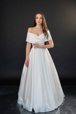 Gri arka planda gelinlik giymiş güzel bir kadın. 