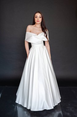 Beyaz gelinlikli güzel bir kadın beyaz arka planda bir stüdyoda duruyor.. 