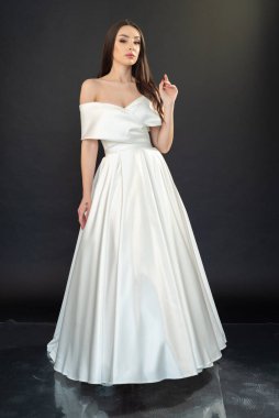 Beyaz gelinlik içinde genç ve güzel bir gelin. Stüdyo çekimi gri arkaplanda 