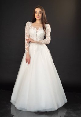 Uzun saçlı, siyah arka planda gelinlik giymiş güzel bir gelinin portresi. 