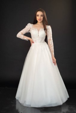 Gri stüdyo arka planında gelinlik içinde genç ve güzel bir gelin. 