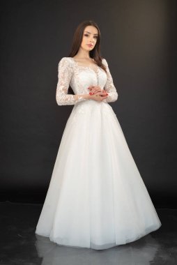 Gri arka planda gelinliği olan güzel bir kız. 