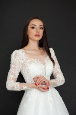 Gri arka planda gelinlik giyen genç bir kadının portresi. 