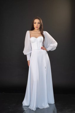 Genç esmer kadın beyaz elbise içinde poz veriyor 