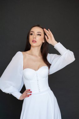 Stüdyo arka planında zarif gelinlik içinde genç ve güzel bir kadın. 