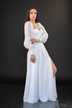 Beyaz elbiseli esmer bir kızın tüm vücut portresi. 