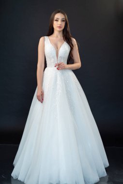 Gelinlik içinde güzel bir gelin ve açık arkaplanda bir buket çiçek. 